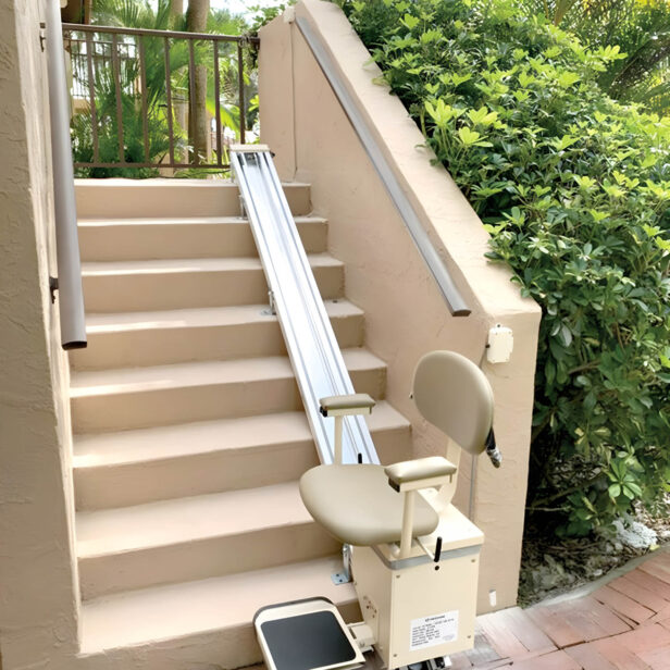 A stairlift is installed alongside an outdoor staircase surrounded by greenery.
